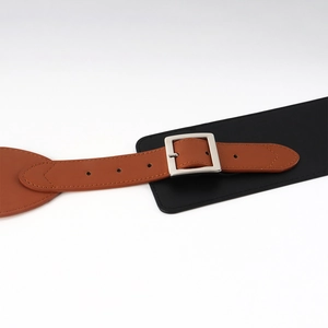 Gros plan sur la ceinture corset noire et marron avec boucle carrée en métal argenté