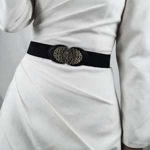 Detail of vintage golden filigree buckle on a black elastic waist belt for dresses