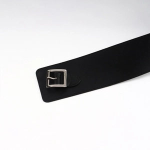 Détail d'une ceinture large noire avec une boucle carrée en métal argenté poli