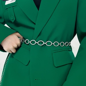 Detail of silver twisted texture oval rings on metal belt over a green blazer