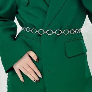 Detail of twisted silver chain belt styled over a dark green blazer for women