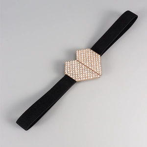 Détail de la boucle cœur en strass sur ceinture élastique noire avec finition or rose