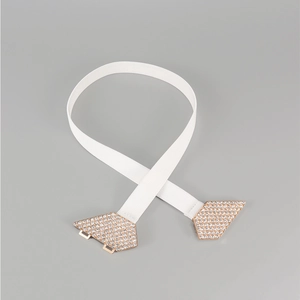 Détail d'une boucle en or rose avec strass blancs étincelants sur ceinture blanche
