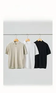 Detail of three cotton cable-knit polo shirts in beige, white, and black with waffle texture