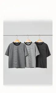 Dettaglio di tre t-shirt a righe in cotone con girocollo in grigio e nero su un supporto