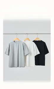 Three men's minimalist t-shirts in grey, white, and black hanging on a metal rod