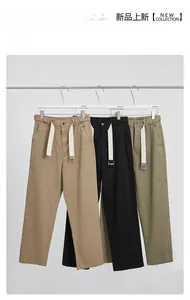 Detailweergave van de kaki, zwarte en groene rechte broek met decoratieve geweven tailleband