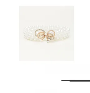 Close-up of pearl waist belt featuring a gold bow buckle with sparkling rhinestones
