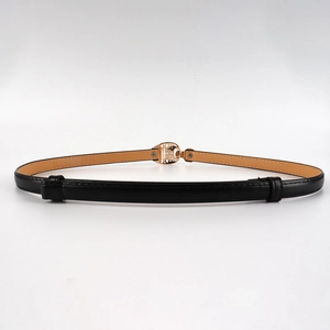 Détail de la ceinture fine en cuir noir avec une boucle dorée ajourée au style vintage