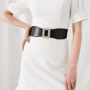 Détail de la large ceinture noire élastique avec boucle en perles et strass sur robe blanche