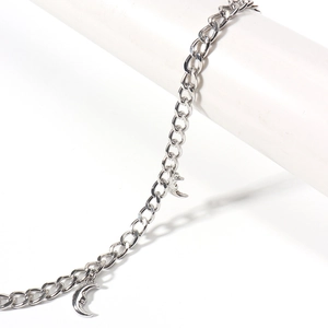 Detailed close-up of a silver crescent moon charm with a face relief on a star-themed body chain