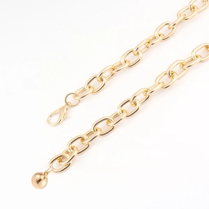 Detail of gold chunky chain belt featuring a lobster clasp and a round ball pendant