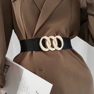 Women's black wide elastic waist belt with a golden triple-ring buckle on a brown blazer