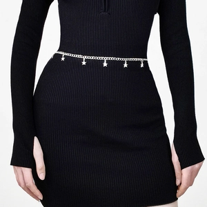 Detail view of silver star charms hanging on a metal body chain for women worn over a dress
