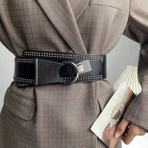 Détail d'une large ceinture punk noire avec rivets argentés et boucle métallique