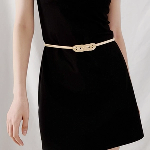 Detail of gold metal spring chain belt with double infinity twist buckle on black dress