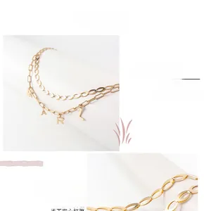 Detail of gold double-layer chain waist belt featuring Eiffel Tower and letter pendants