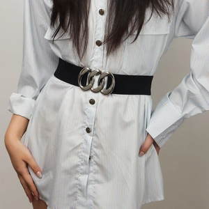 Women's black wide elastic belt with triple interlocking silver rings over striped shirt