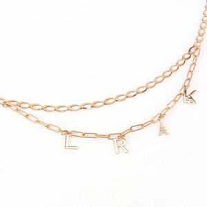 Detailed shot of golden double-layer waist chain featuring Eiffel Tower and letter pendants