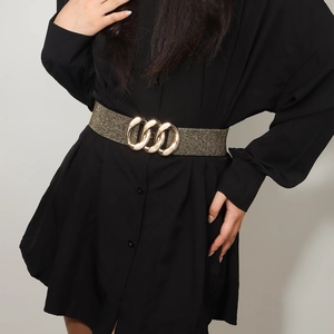 Detail of wide elastic waist belt with triple gold interlocking rings on black dress