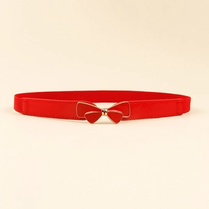 Close-up of red elastic belt featuring a glossy bow buckle with gold metallic edges