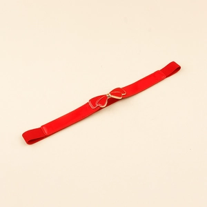 Close-up of a red bow buckle with gold trim on an elastic skinny belt for dresses