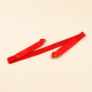 Detail of red elastic waist belt with gold heart buckle and glossy leather finish