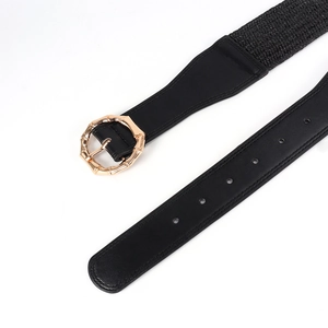 Detail of golden bamboo-style metal buckle and black elastic waist belt with leather finish