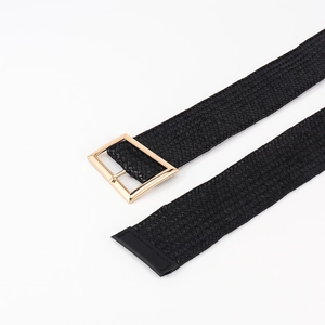 Detail of slim black textured belt showing a polished gold rectangular pin buckle