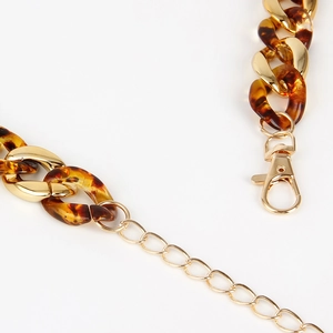 Macro detail of leopard resin and gold metal chain link belt with lobster clasp closure