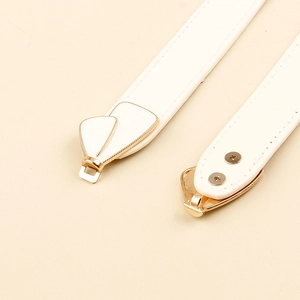 Detailed close-up of white leather belt with gold heart buckle and fine stitching