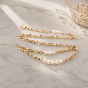 Détail d'une chaîne de taille dorée double couche avec perles et pendentif pièce