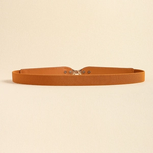 Detail of tan elastic belt featuring a golden interlocking metal buckle and rivet accents
