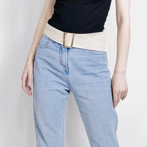 Beige elastic woven belt with a gold metal buckle paired with jeans and a black top