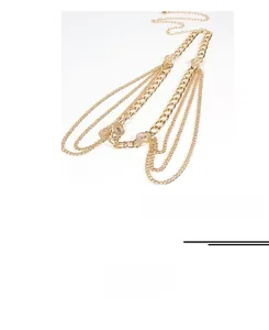 Vue macro d'une chaîne de corps punk dorée multicouche avec pendentifs pièces vintage