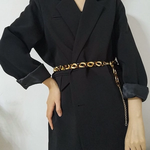 Detailed view of leopard print acrylic and gold metal chain belt on black blazer
