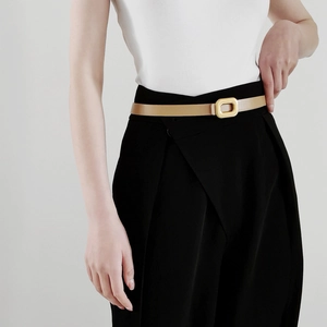 Close-up of minimalist khaki leather slim belt with a polished gold rectangular buckle
