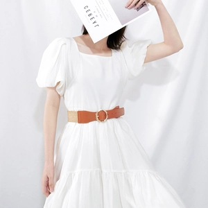 Close-up of a brown elastic waist belt with a gold bamboo-style buckle on a white dress