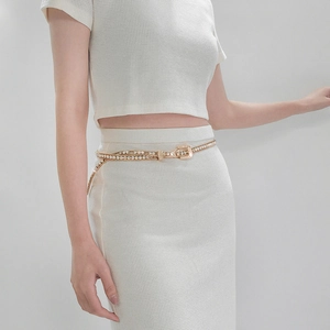 Detail of elegant gold rhinestone waist chain with delicate buckle on white knitwear
