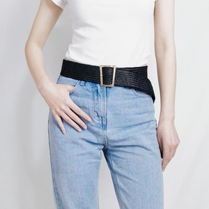 Detailed view of women's black braided belt with a polished gold square metal buckle