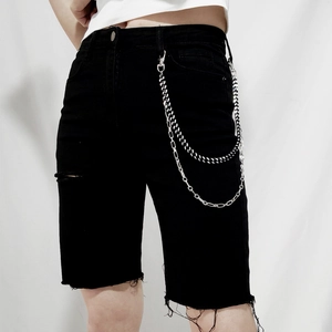 Détail de la chaîne de pantalon double couche en argent sur un short en jean noir