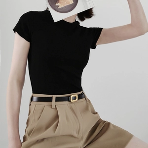 Close-up of thin black PU leather belt with a golden square buckle on khaki shorts