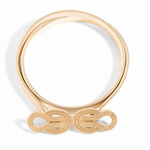 Détail d'une ceinture chaîne dorée élastique avec boucle à double nœud torsadé sur fond blanc