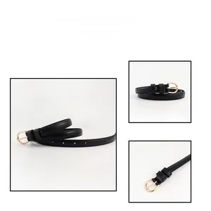 Detail view of a black slim belt with a gold horseshoe buckle on a white background