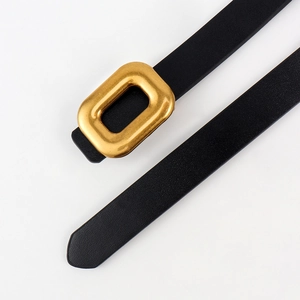 Close-up of thin black leather belt with a matte gold rectangular buckle and fine texture