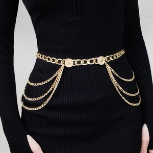 Détail de la chaîne de corps punk dorée avec triple pompons et pièces sur robe noire
