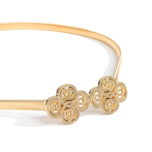 Détail d'une ceinture élastique dorée avec chaîne texturée et boucle ajourée