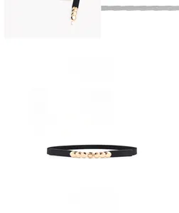 Ceinture élastique noire avec cinq clous en métal doré sur un fond blanc neutre
