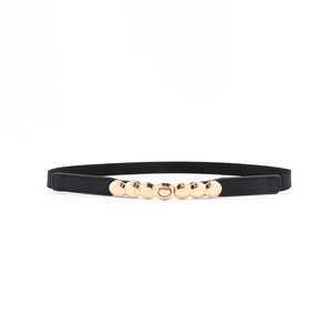 Détail d'une ceinture élastique noire dotée d'une boucle ronde décorative en métal doré