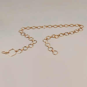 Détail des maillons de la chaîne de taille en métal hexagonal doré poli brillant